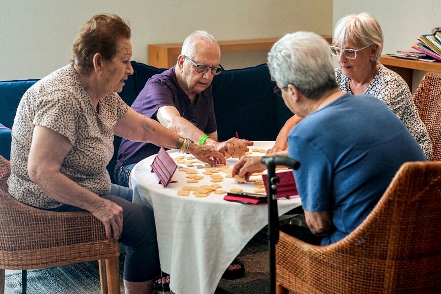 Elderly people play a tile game in a hotel lobby in Tiberias on June 21, 2024, where hundreds of Israelis have been housed after their displacement from their homes near the border with Lebanon