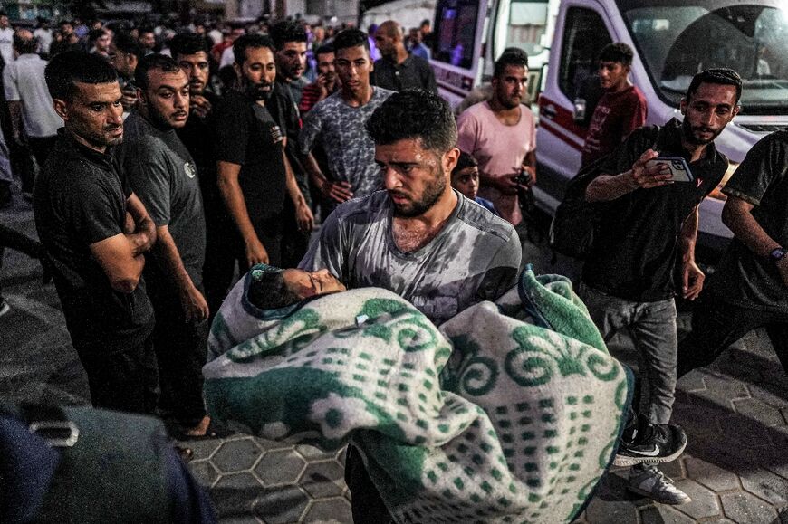 A man carries a girl who was injured by Israeli bombardment on al-Bureij outside the Aqsa Martyrs hospital in Deir el-Balah in the central Gaza Strip on June 4, 2024 