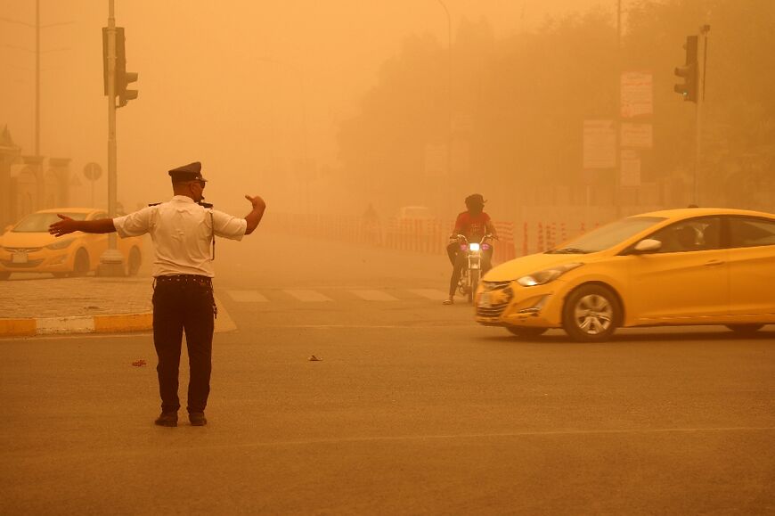 A traffic policeman directs traffic flow in Nasiriyah during a heavy dust storm