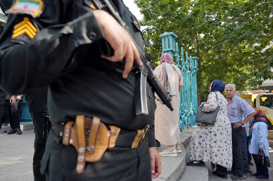 A policeman stands guard outside a polling station during voting in Tehran