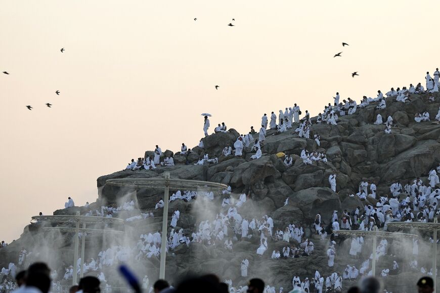 Hajj pilgrims on Mount Arafat walk under mist dispensers installed to help them cope with scorching temperatures