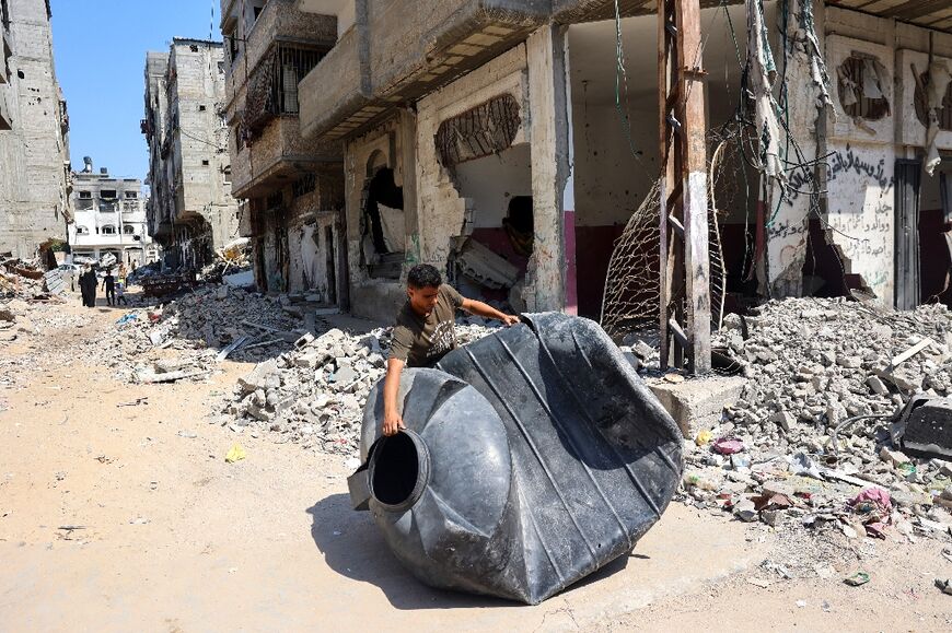 A man carries a water tank damaged during Israeli bombardment to have it repaired in Khan Yunis in the southern Gaza Strip