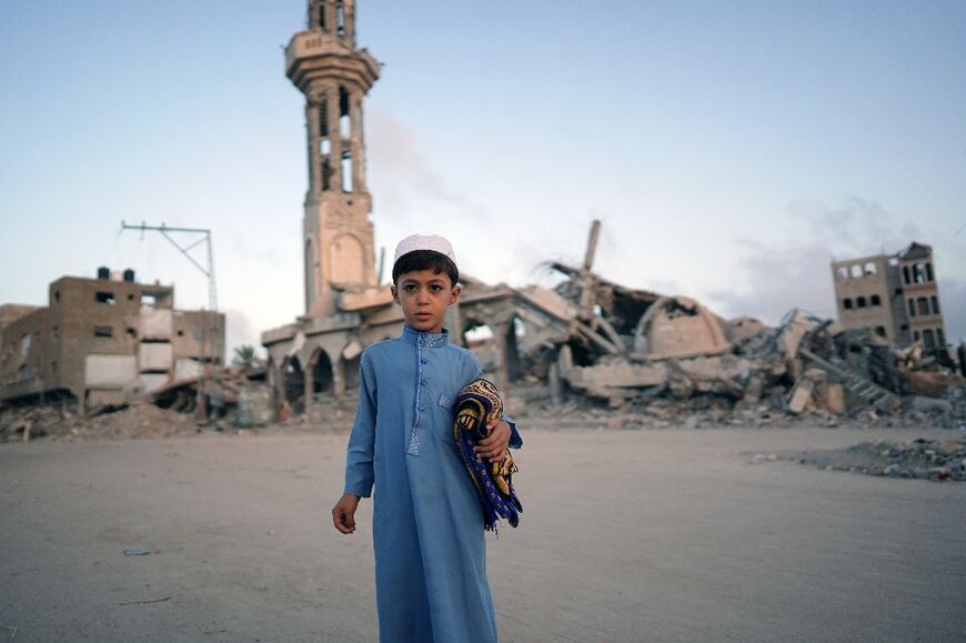 A Palestinian boy, carrying his prayer mat, poses for a picture before joining the morning Eid al-Adha prayer in Khan Yunis, southern Gaza