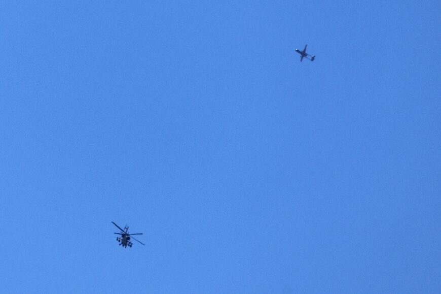 An Israeli military helicopter and a drone fly above the southern border area with the Gaza Strip 