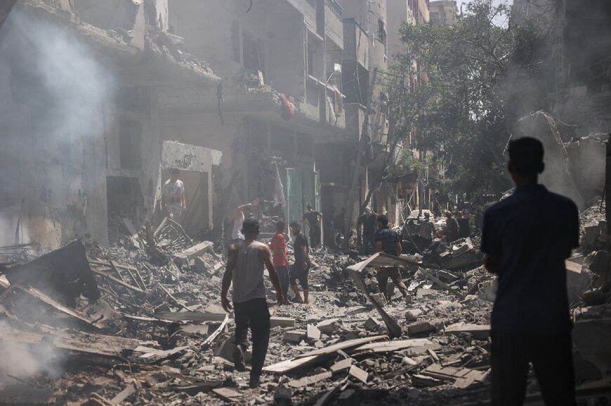 Palestinians walk on the rubble of destroyed buildings following an operation by Israeli forces in the Nuseirat refugee camp, central Gaza