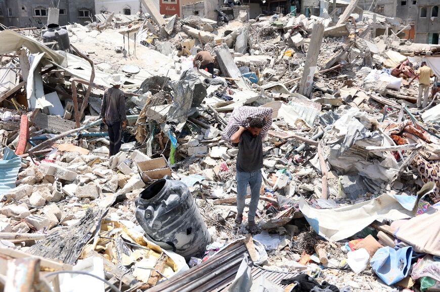 A Palestinian man carries goods he retrieved from under the rubble of a destroyed building in the Jabalia refugee camp in the northern Gaza Strip