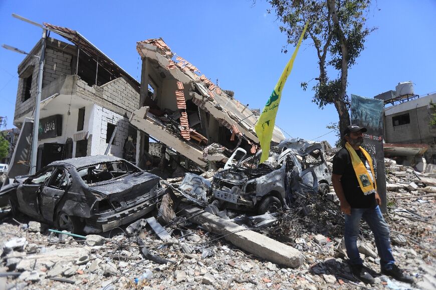 A Hezbollah flag is jammed into the wreckage of a vehicle in the aftermath of Israeli fire on the southern Lebanese village of Aita al-Shaab