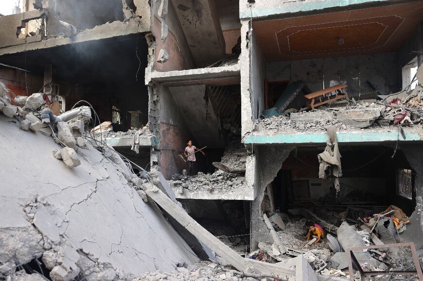 Palestinians children search through the rubble of their home in the Nuseirat camp in the central Gaza Strip on June 9, 2024