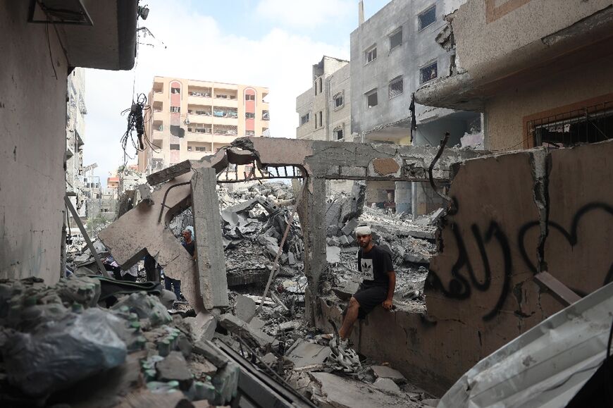 A Palestinian man sits in front of a destroyed building the day after the Israeli operation to free four hostages held in Gaza