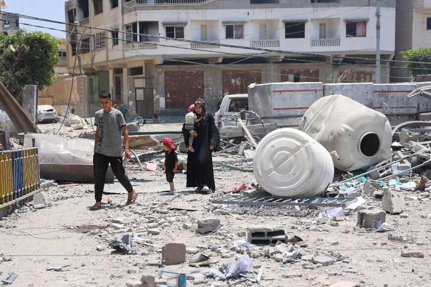 Palestinians next to rubble following Israeli bombardment in Gaza City, more than eight months into the Israel-Hamas war