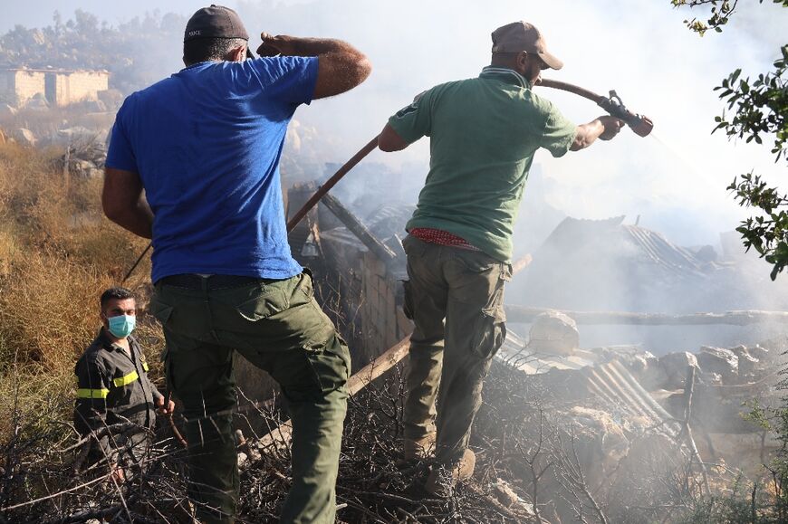 Lebanese firefighters and residents douse a fire after Israeli shelling in the border village of Shebaa