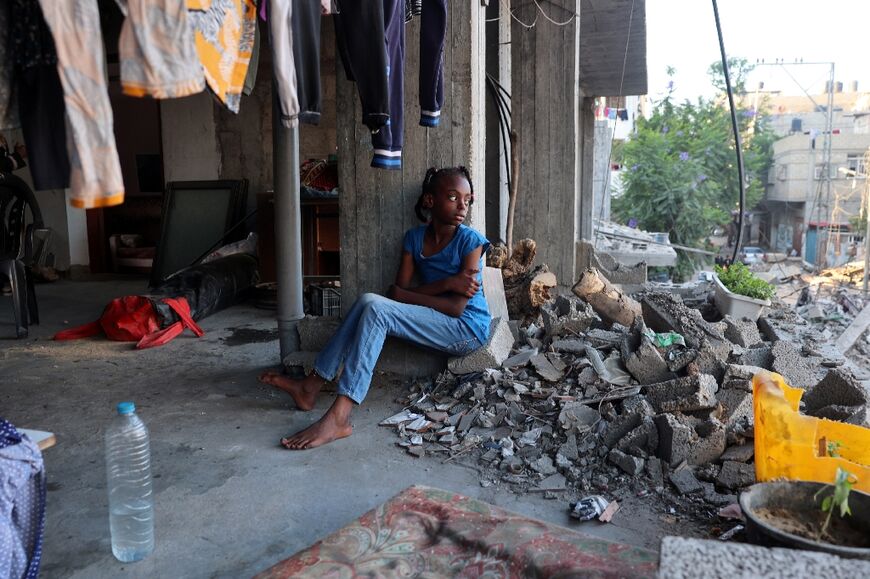 A displaced Palestinian girl sits in a damaged building used as a temporary shelter in Bureij refugee camp