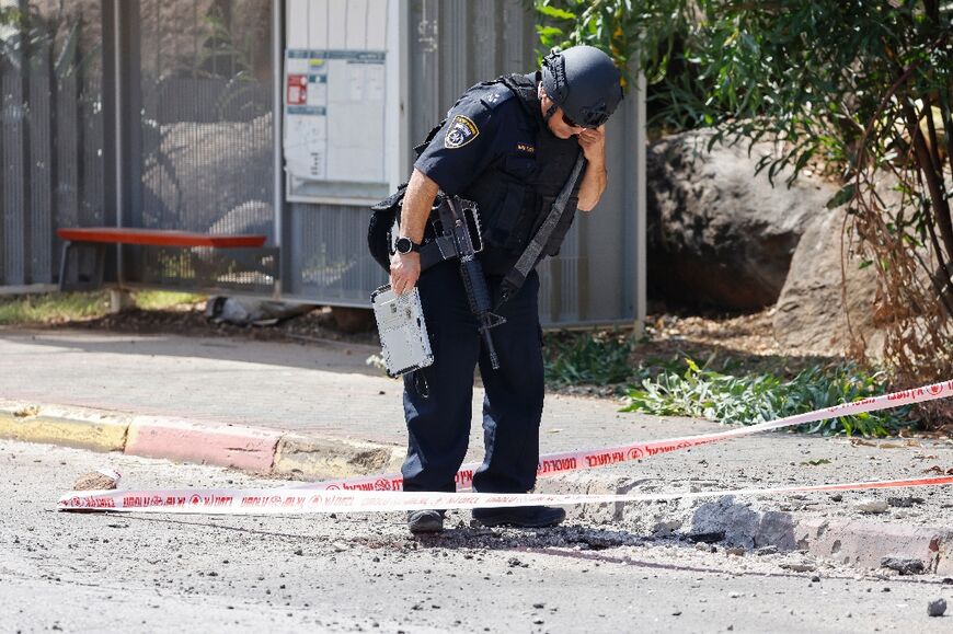 Members of Israeli security forces inspect sites where rockets launched from southern Lebanon fell in Kiryat Shmona in northern Israel near the Lebanon border, on June 19, 2024