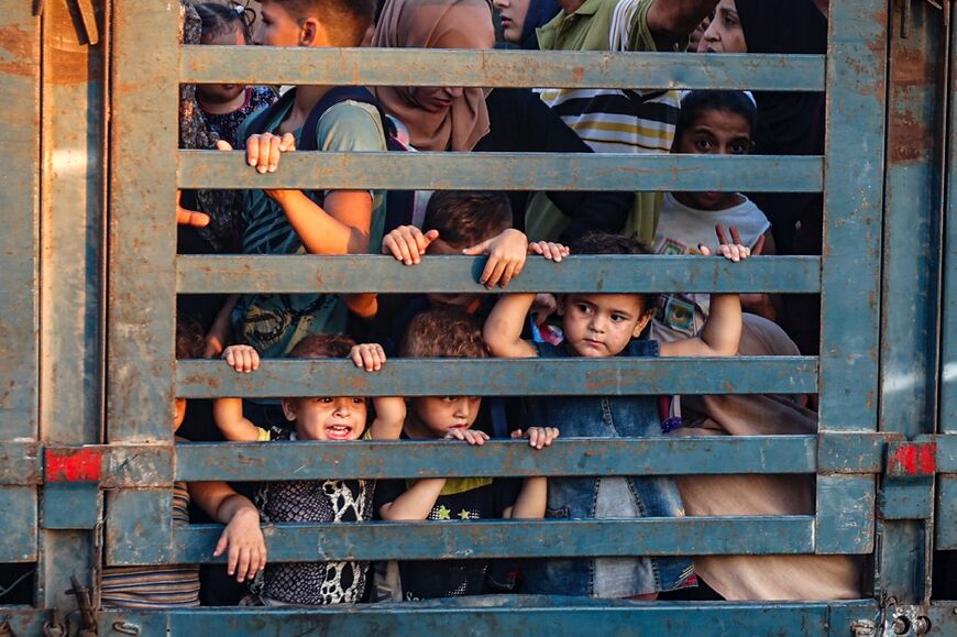 Children look on from the back of a truck as Palestinians flee Al-Bureij refugee camp, central Gaza, an area where the Israeli military said it would 'operate forcefully' against militants