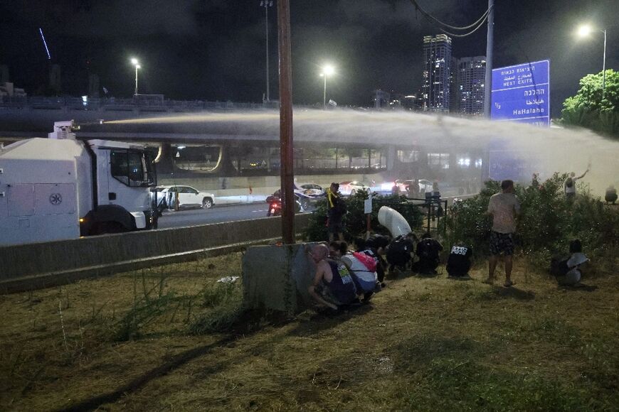 Israeli authorities deploy water canon to clear anti-war protesters blocking a highway in Tel Aviv