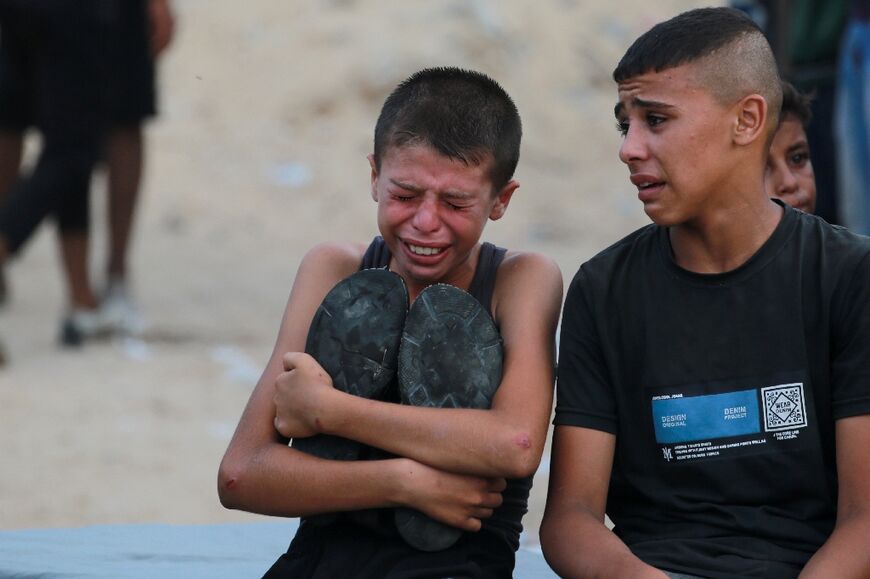 A Palestinian boy cries as killed Gazans are brought for burial outside Nasser hospital in Gaza's Khan Yunis following Israeli bombardment east of the city 