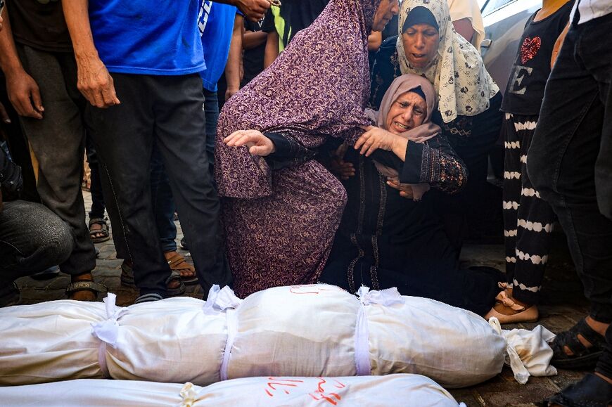 Palestinian women mourn over the shrouded bodies of 3 young girls from the al-Rai family killed in an Israeli bombing in Deir el-Balah in the central Gaza Strip