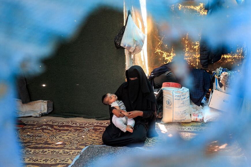 A woman with an infant sits in a tent at a camp for displaced people in Khan Yunis in the southern Gaza Strip on July 11, 2024