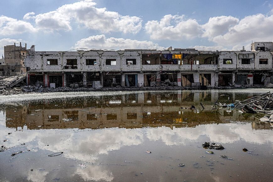 Sewage water from collapsed underground pipes covers an area by destroyed buildings in Khan Yunis in the southern Gaza Strip