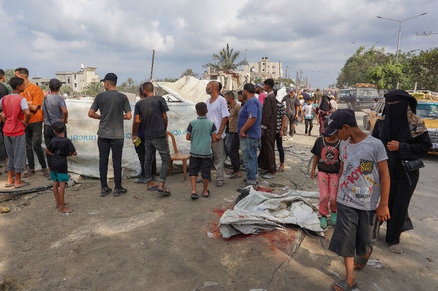 Palestinians look at a covered blood stain on the ground at the site of Israeli bombardment in Gaza's Al-Mawasi