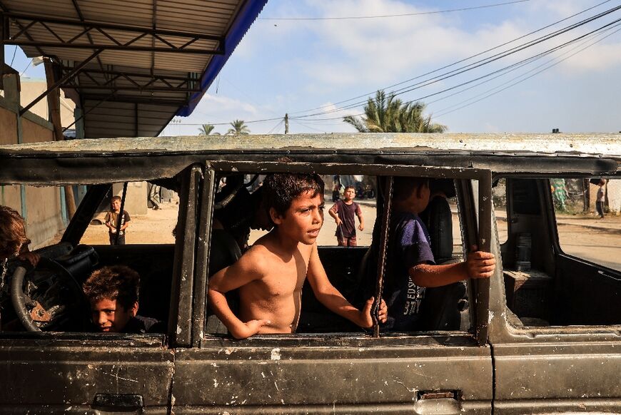 Displaced children play in a burned out vehicle in Deir al-Balah city, central Gaza 