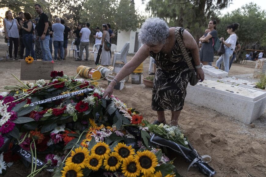 Former hostage Ruti Munder arranges flowers on the grave of her husband Avraham Munder who died in captivity in Gaza after being taken by Palestinian militants who attacked Israel