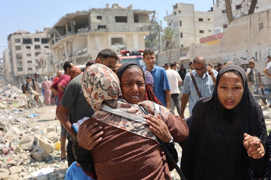 Palestinians near the site of an Israeli strike on a school housing displaced Gazans