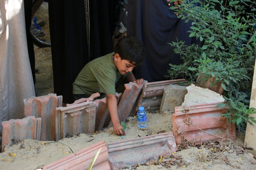 A child places leaves on the tomb of a family member in the southern Gaza Strip