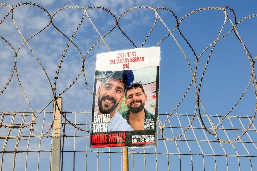 A poster identifying Israeli hostages Gali and Ziv Berman is raised on the border fence