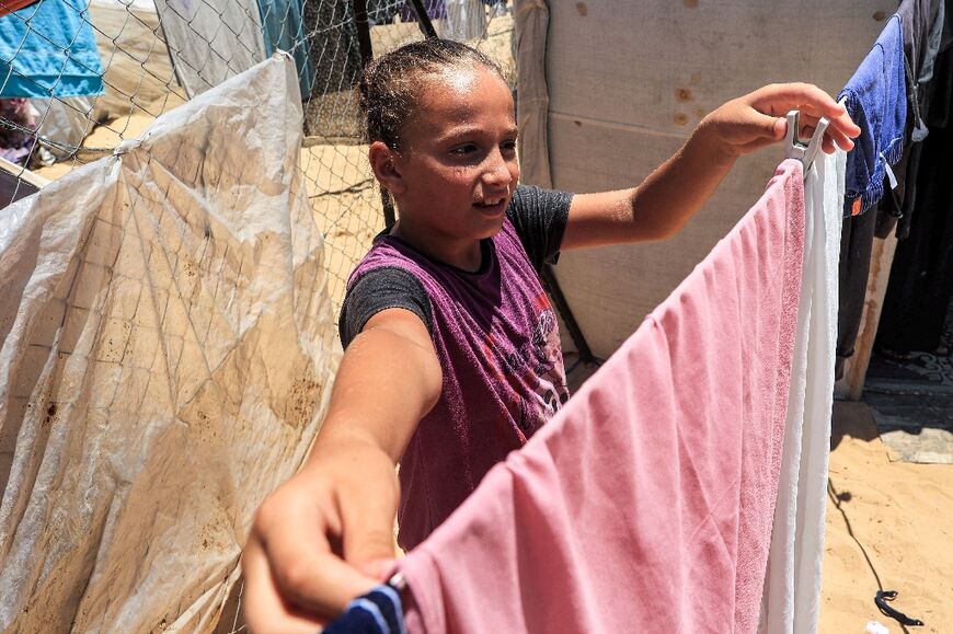 A girl hangs clothes out to dry at a camp for displaced people in Khan Yunis in the southern Gaza Strip 