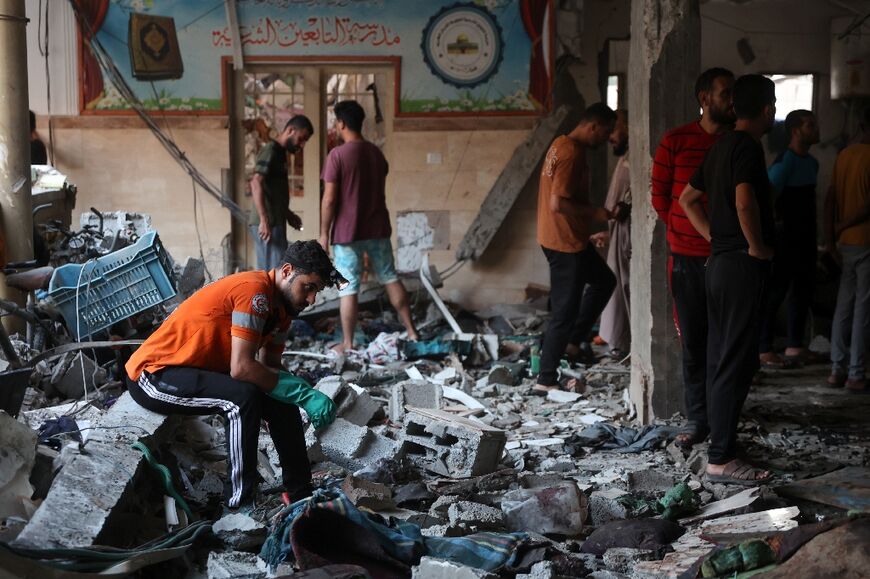 People check the damage inside a school where displaced Palestinians were sheltering in Gaza City, after an Israeli strike