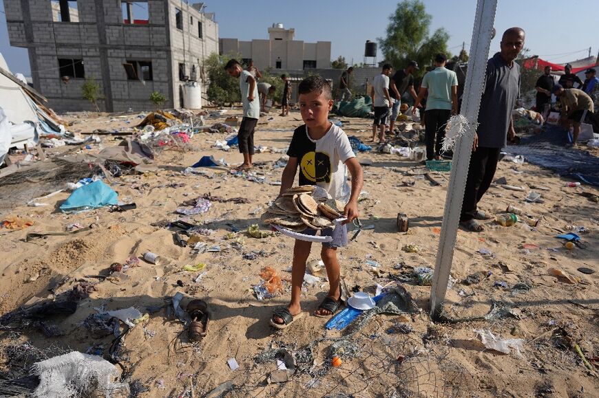 A Palestinian child carries a tray with bread at the Mawassi camp in the southern Gaza Strip