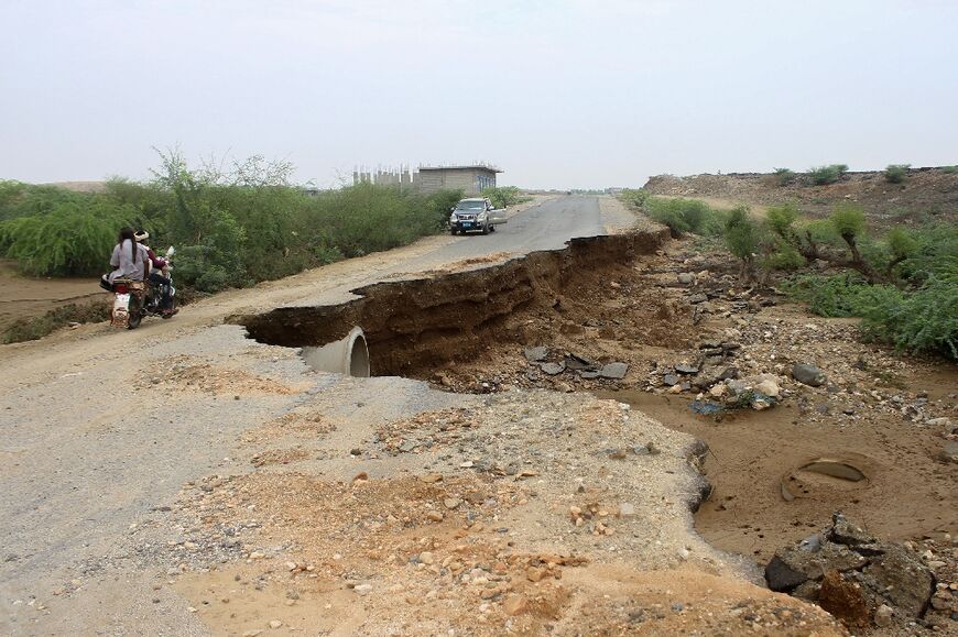 Motorists negotiate a road partly swept away by flash flooding in the Hajjah province of northwestern Yemen