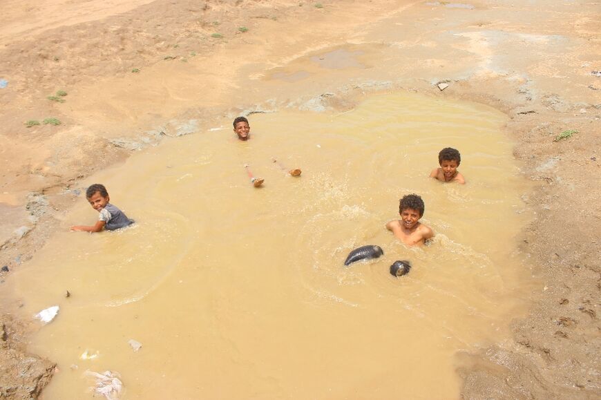 Children play in a large puddle left by heavy rains near a displaced persons' camp in Hajjah province in northwestern Yemen