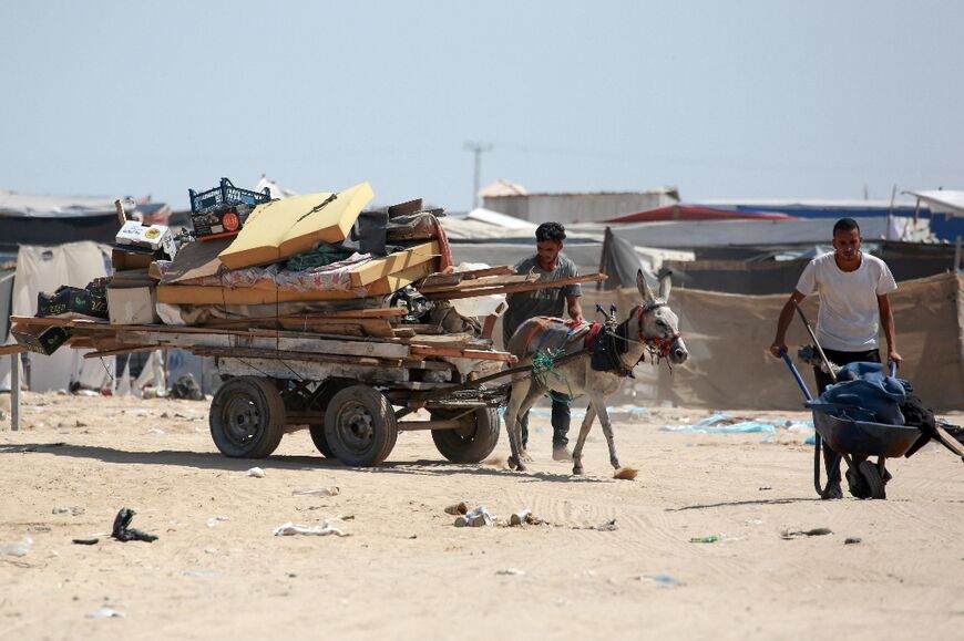 Palestinians move their belongings from a makeshift camp for displaced people in Khan Yunis, southern Gaza, after Israeli tanks took position on a hill overlooking the area