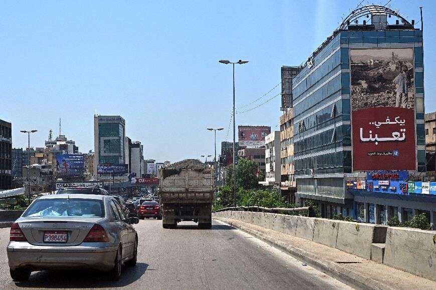 Cars drive past a giant billboard that reads 'Enough, we are tired, Lebanon doesn't want war' on a street in Beirut