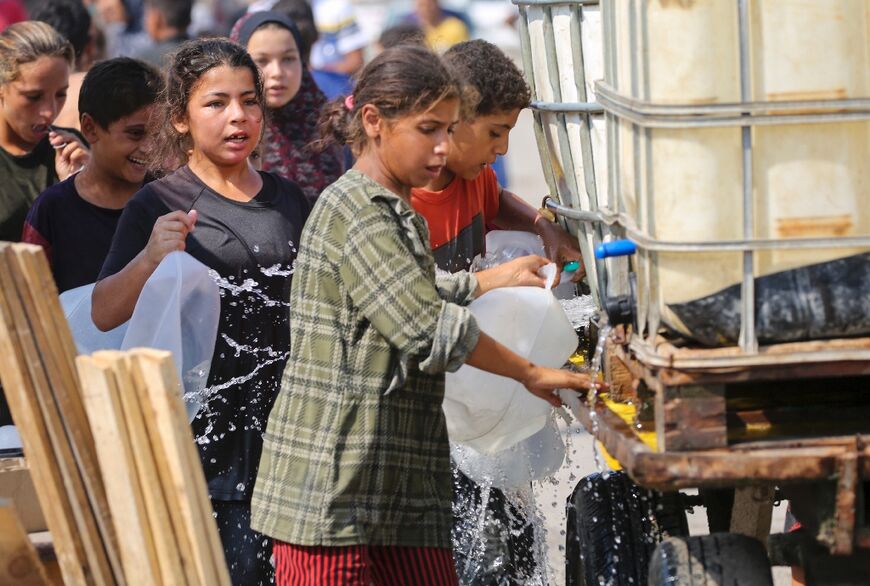 Children line up to fill containers with water at a makeshift camp for displaced Palestinians in Deir el-Balah, central Gaza