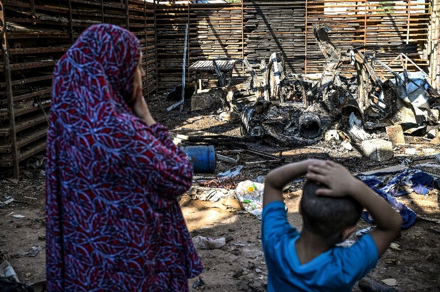 A Palestinian woman and a child check the mangled wreck of a car destroyed in an Israeli strike on Jenin