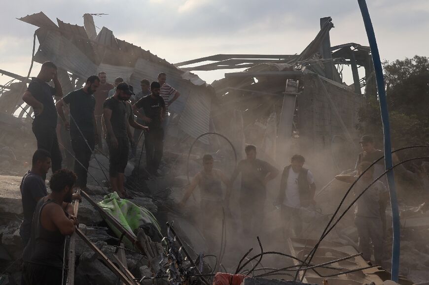 Palestinians inspect the site of an Israeli strike in Al-Zawaida, central Gaza, which the civil defence agency said killed 15 people from a Palestinian family