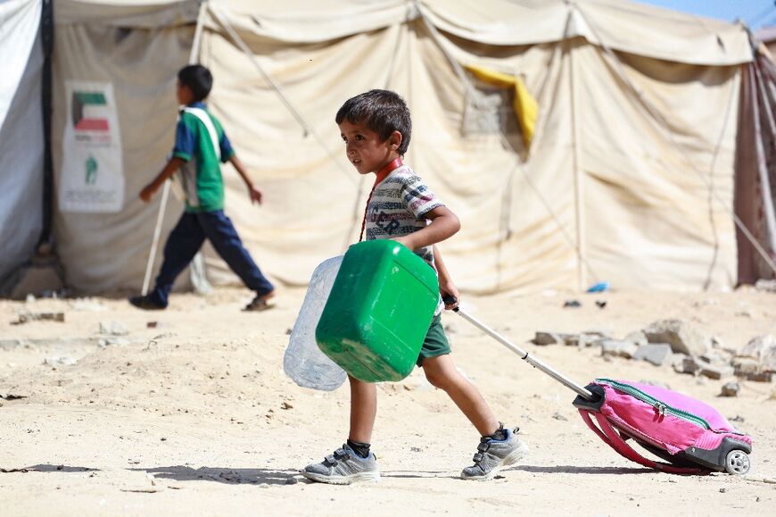 A Palestinian child drags along his bag as people flee the Hamad residential district and its surroundings in Khan Yunis