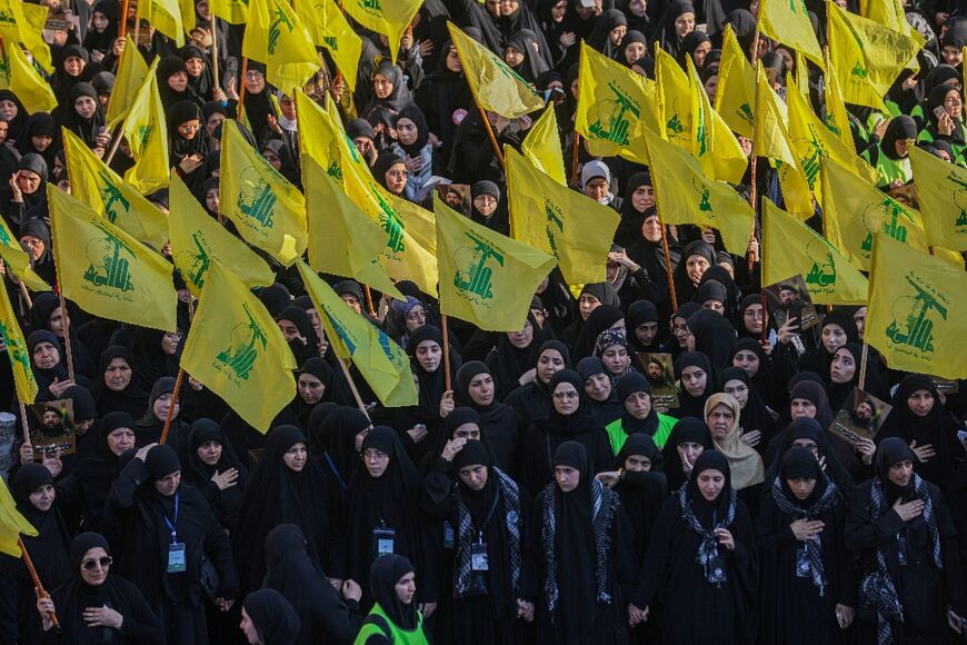 Black-clad women in the southern suburbs of Beirut wave yellow Hezbollah flags as they join the funeral procession for slain commander Fuad Shukr