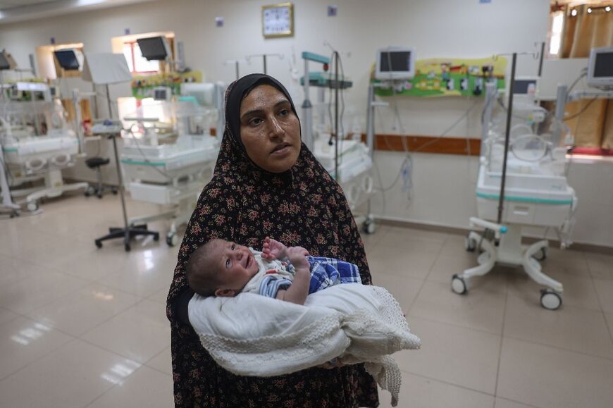 A Palestinian woman prepares to evacuate with her newborn from the Al-Aqsa Martyrs Hospital 