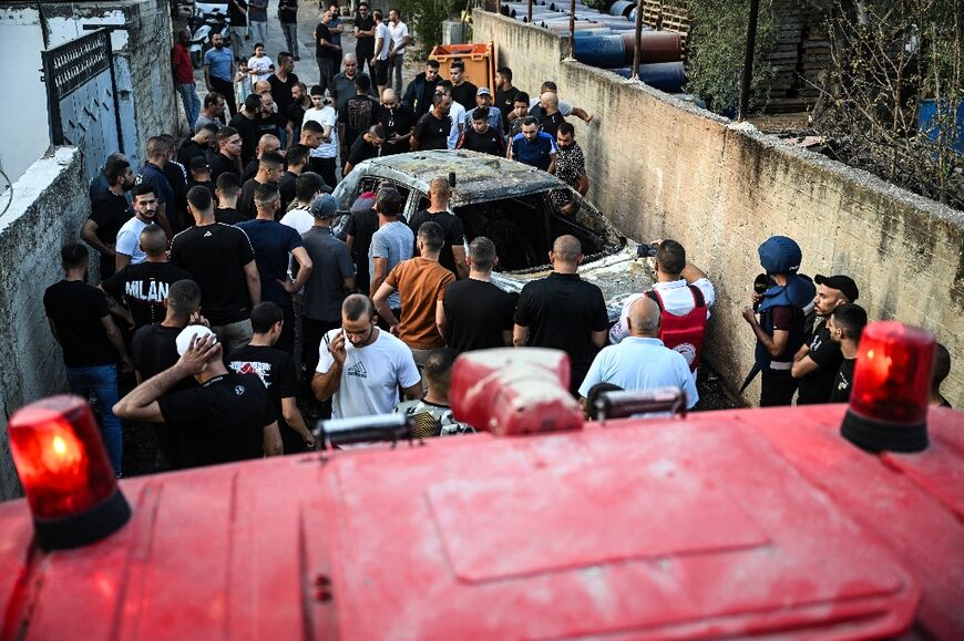 People check a burnt car in the town of Zababdeh, southeast of Jenin in the occupied West Bank following an Israeli army raid 