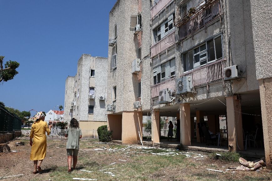 In Acre, Israel, residents pass a building damaged by a rocket fired from Lebanon 