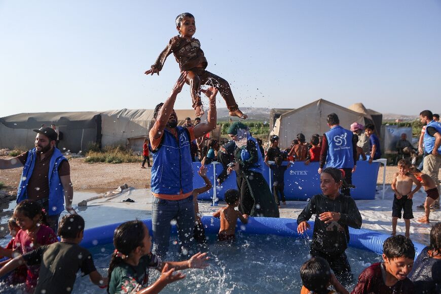 A volunteer throws a child into the air at the Kafr Naseh camp, in the rebel-held part of Aleppo province