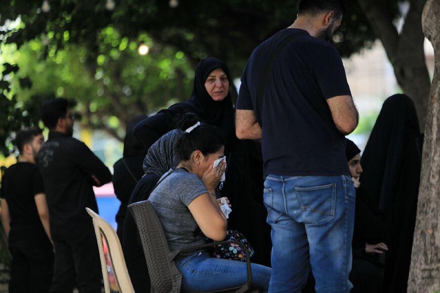 People wait at the scene of the strike, where rescuers continued to dig and the death toll rose