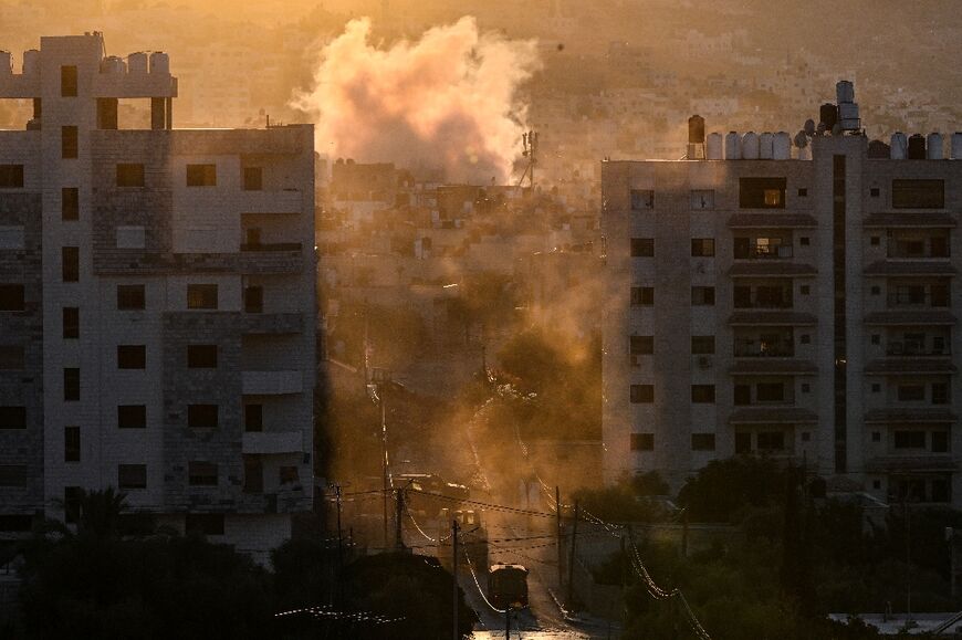 Israeli military vehicles and rising plumes of smoke during an ongoing raid in the occupied West Bank's Jenin refugee camp