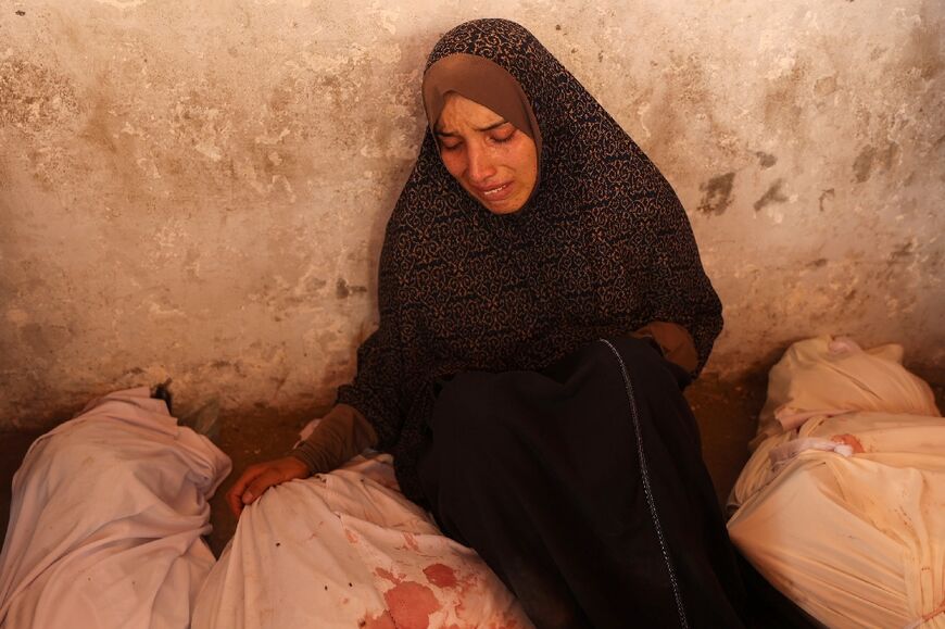 A woman mourns over bodies of relatives after an Israeli strike on a school housing displaced Palestinians in Gaza City