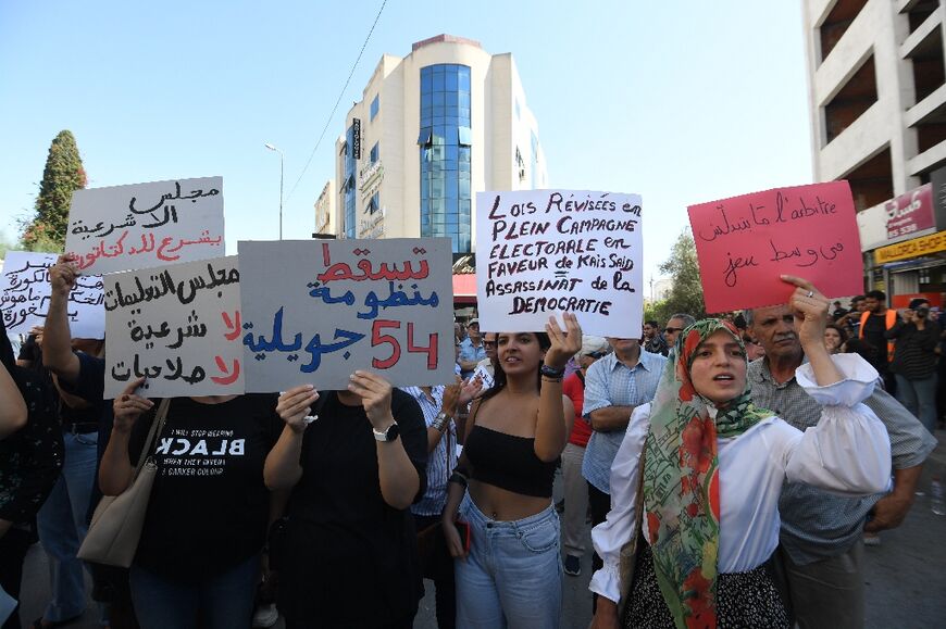 Tunisians chant slogans and wave placards during a demonstration in front of parliament