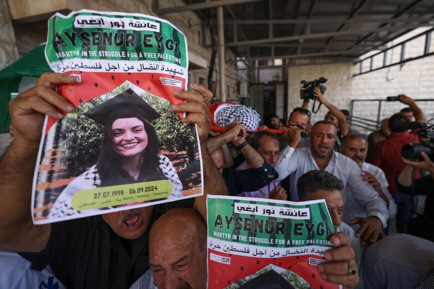 Palestinians hold pictures of Aysenur Ezgi Eygi during a memorial procession for the slain activist